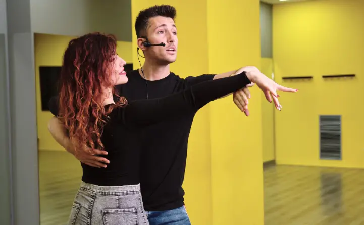 A professional dance instructor coaching a couple through their first dance routine
