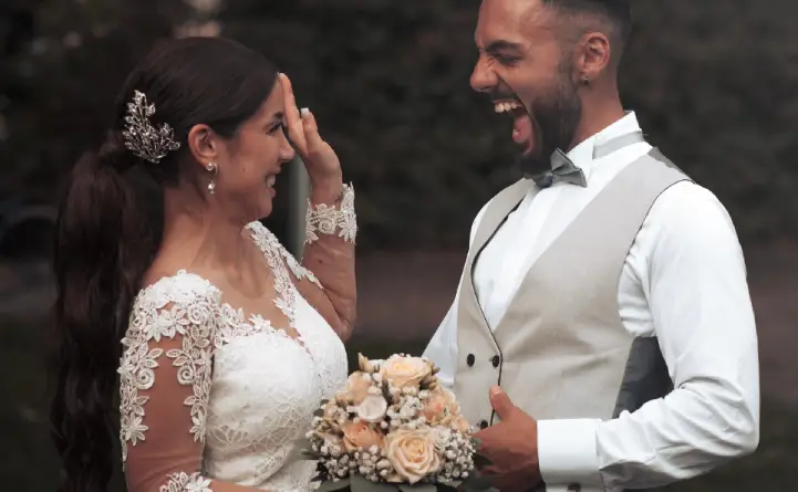  A bride and groom laughing after a playful misstep during their wedding dance practice