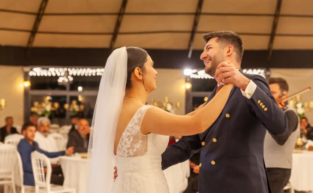 A newlywed couple sharing their first dance under soft glowing lights, surrounded by guests